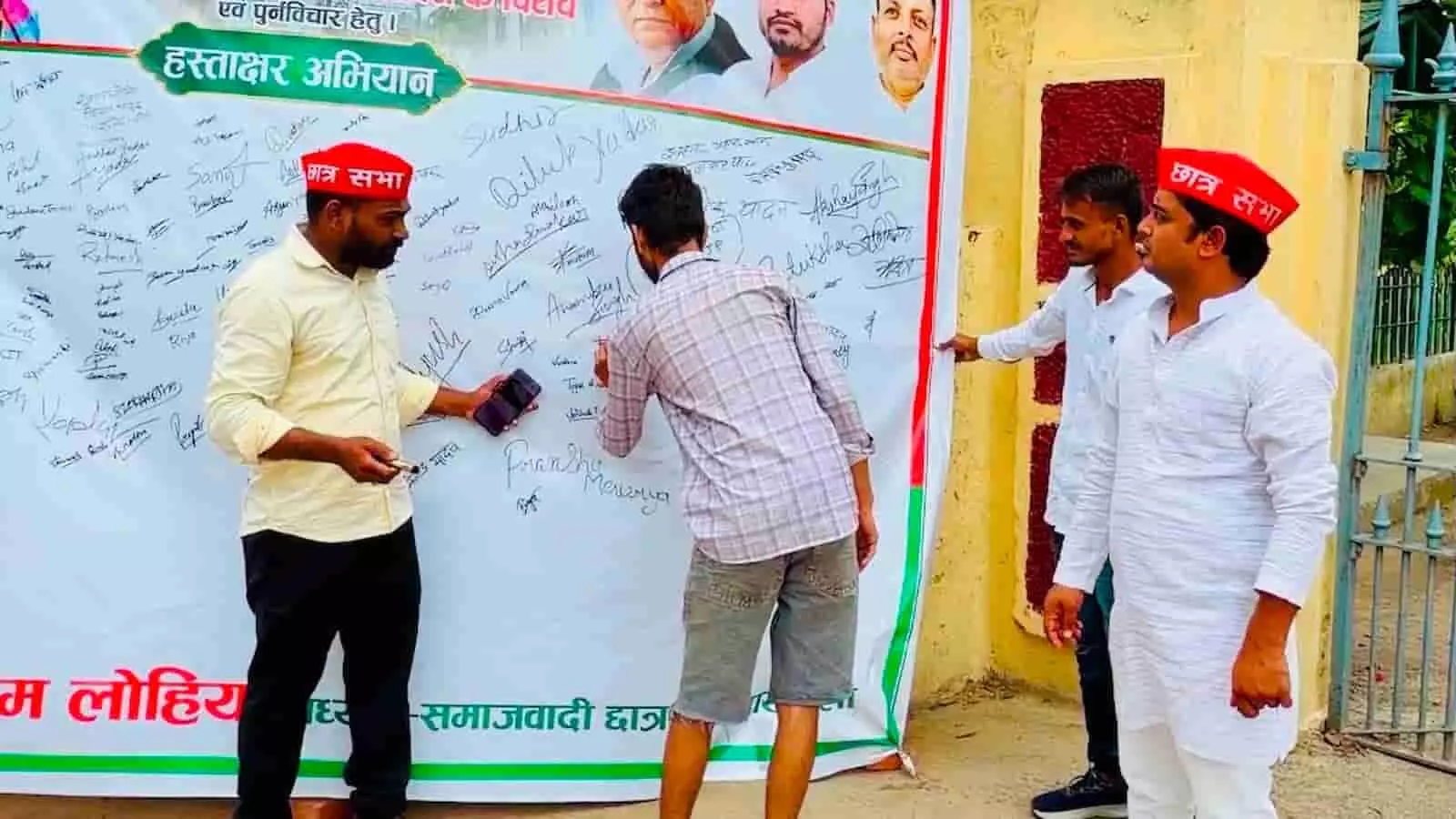फिरोज गांधी डिग्री कॉलेज के पास लगे बैनर पर हस्ताक्षर करते युवा और सपा छात्रसभा कार्यकर्ता।