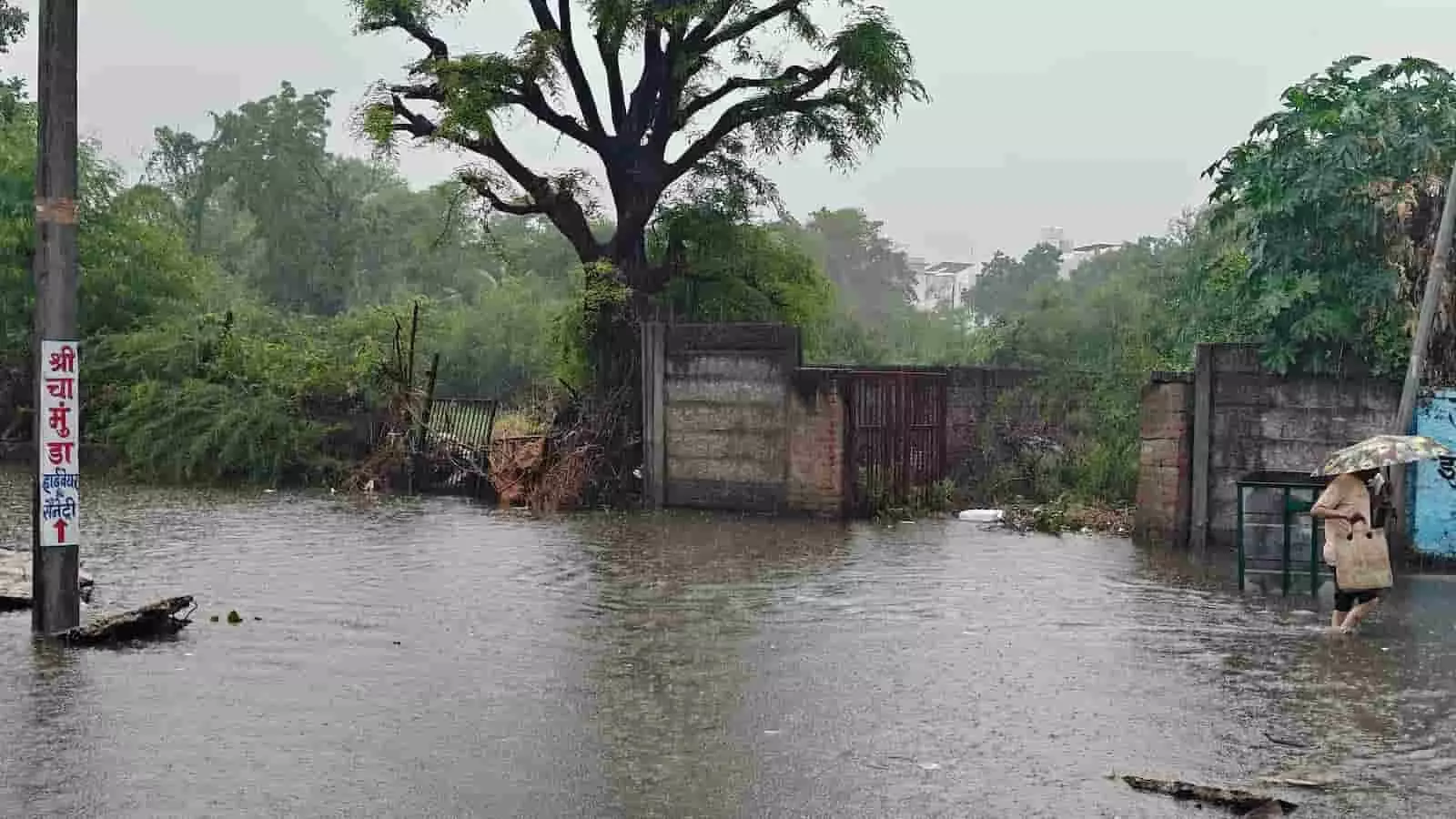 तस्वीर में गंगापुर क्षेत्र की जलभराव वाली सड़क पर छाता लेकर चलते एक व्यक्ति को देखा जा सकता है।