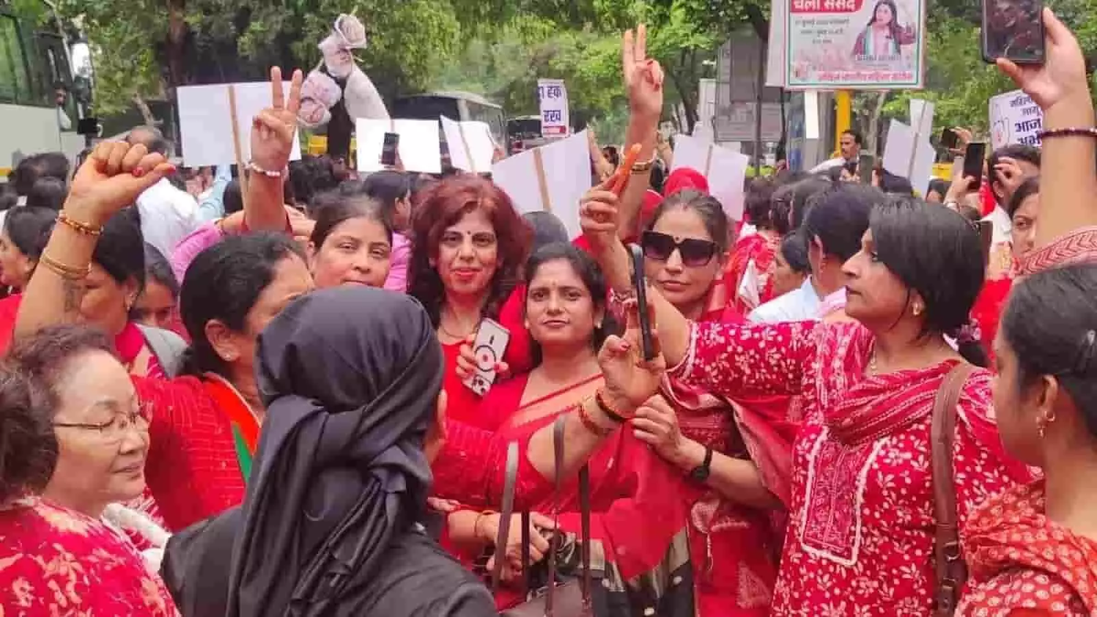 तस्वीर में दिल्ली की सड़क पर हाथों में तख्तियां और मोबाइल लिए लाल कपड़ों में नारेबाजी करती महिला कांग्रेस कार्यकर्ता दिख रही हैं।