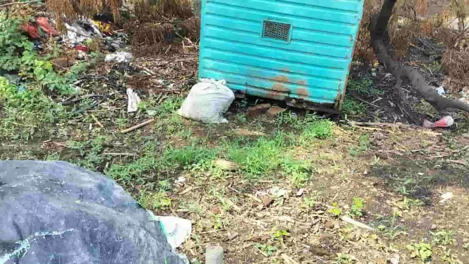 विवादित जमीन पर रखा नीला ढांचा और जलने के बाद बिखरा मलबा दिख रहा है।