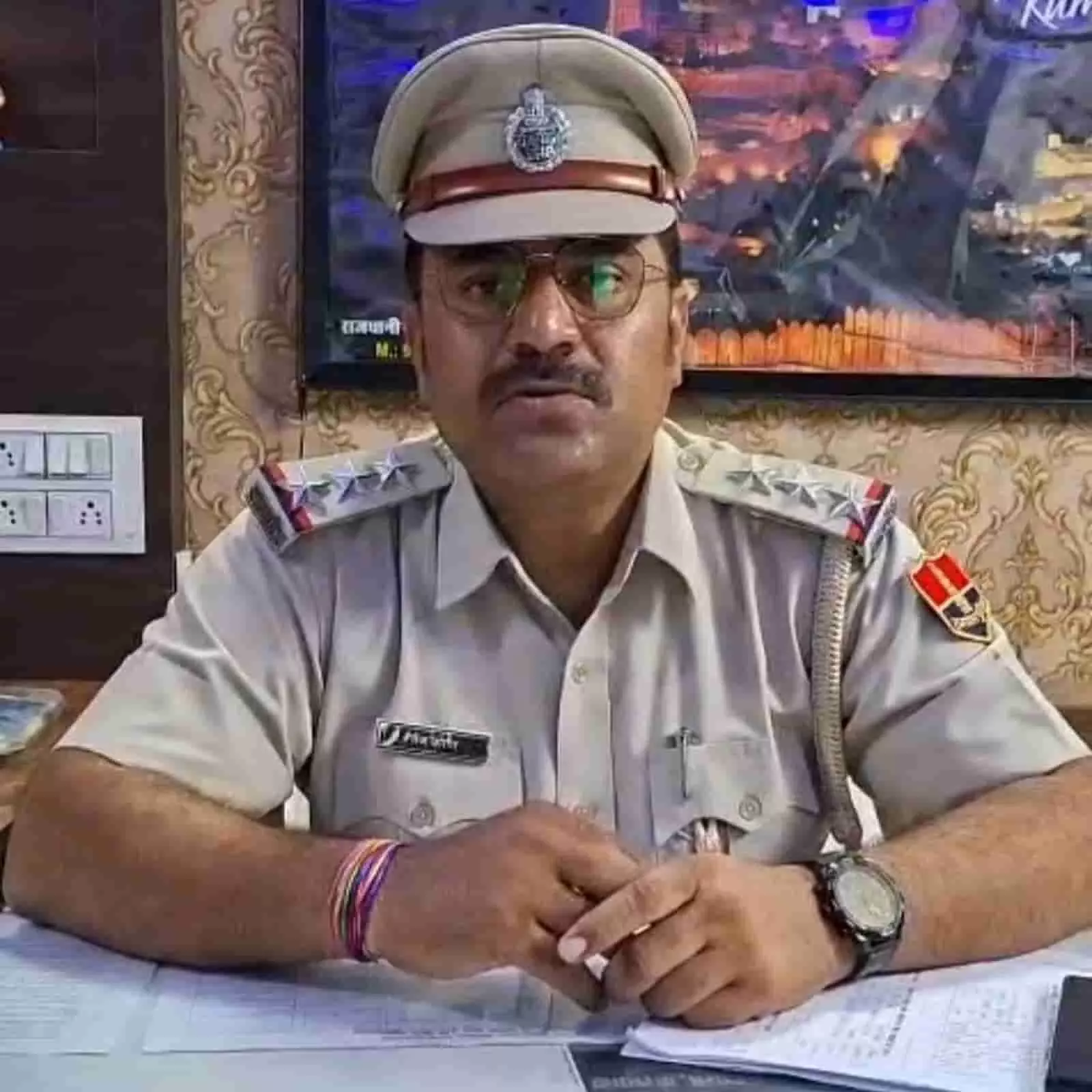 तस्वीर में पुलिस वर्दी पहने थानाधिकारी तेजकरण केलवाड़ा थाने में मेज के पीछे बैठे हुए हैं।