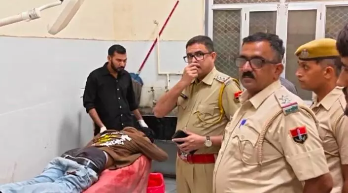 अस्पताल में बिस्तर पर पड़े घायल युवक की जांच करते राजस्थान पुलिस के अधिकारी।