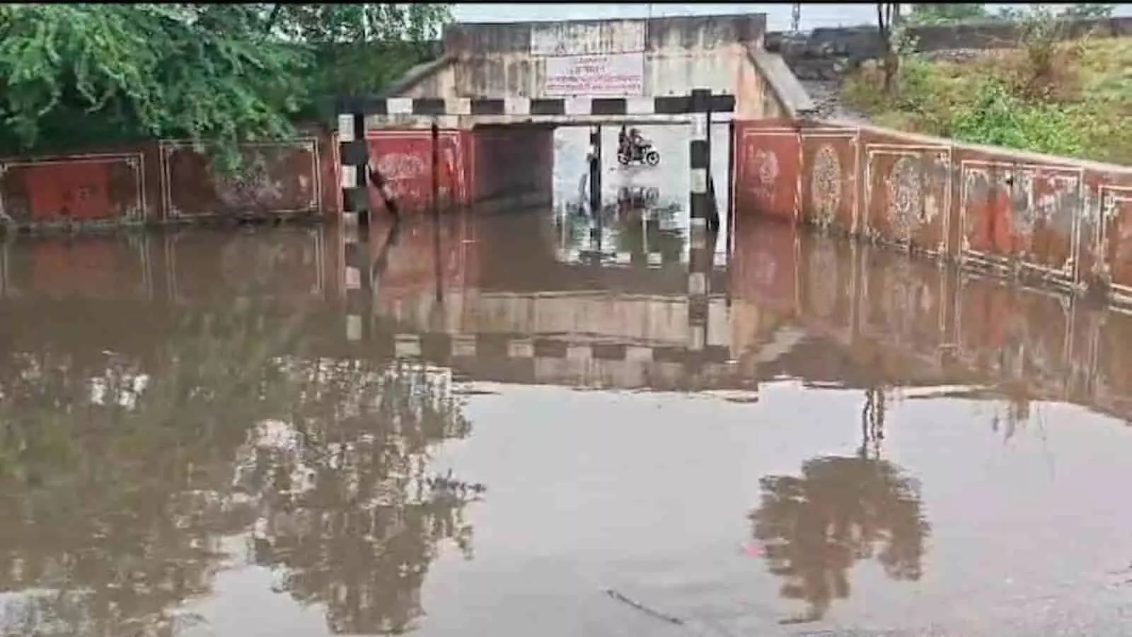 जलभरे रेलवे अंडरब्रिज से होकर गुजरती एक मोटरसाइकिल भीलवाड़ा में दिख रही है।