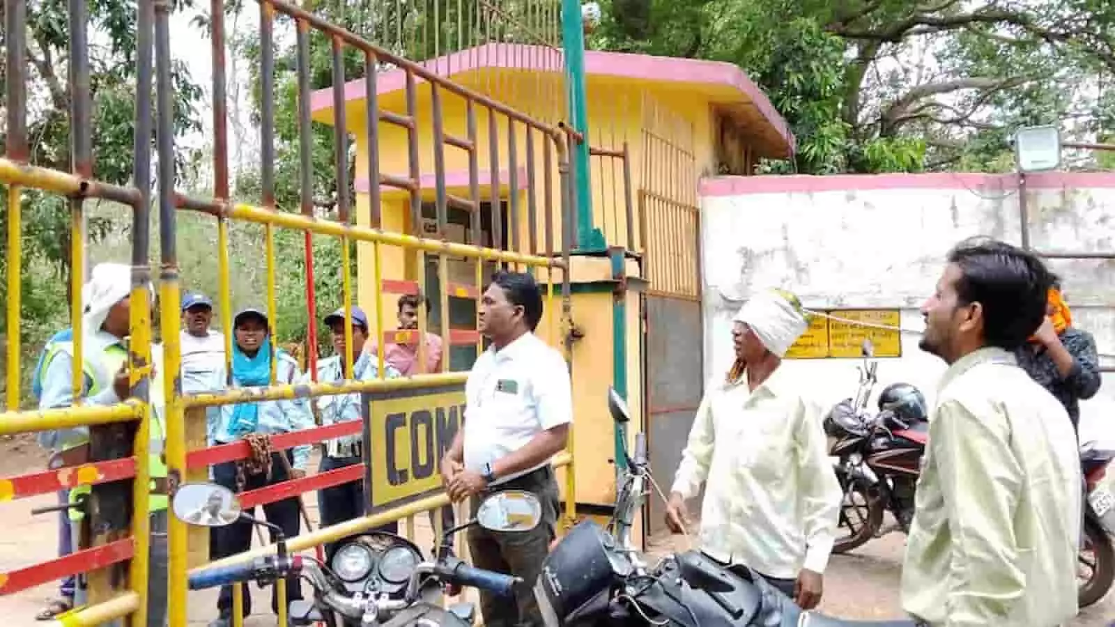 तस्वीर में पीले सुरक्षा गेट के बाहर खड़े ग्रामीण और सुरक्षा गार्ड आपस में बात करते दिख रहे हैं। तस्वीर में पीले सुरक्षा गेट के बाहर खड़े ग्रामीण और सुरक्षा गार्ड आपस में बात करते दिख रहे हैं।