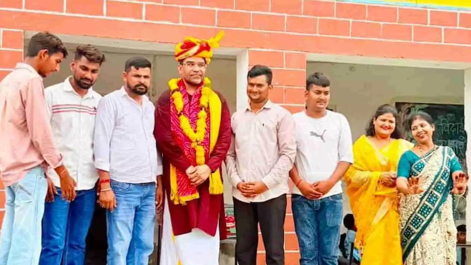 तस्वीर में शिक्षक राजकुमार शर्मा और अन्य लोग विद्यालय के सामने विदाई समारोह में खड़े हैं।