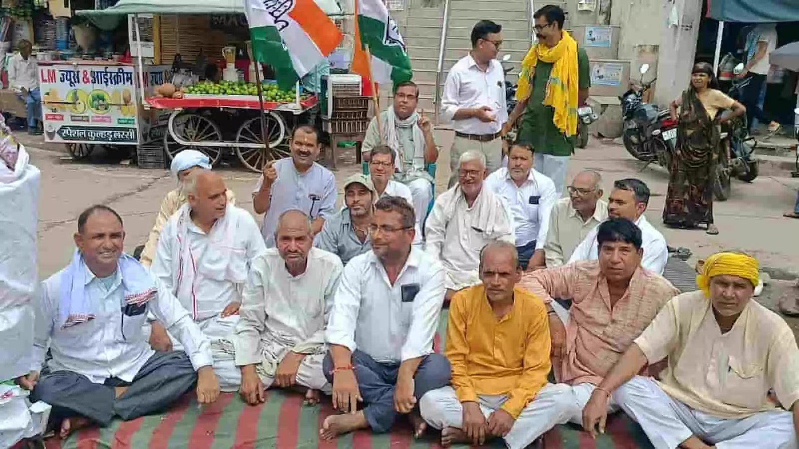 डीग के चौराहे पर विरोध प्रदर्शन के दौरान बैठे हुए कांग्रेस कार्यकर्ता। डीग के चौराहे पर विरोध प्रदर्शन के दौरान बैठे हुए कांग्रेस कार्यकर्ता।