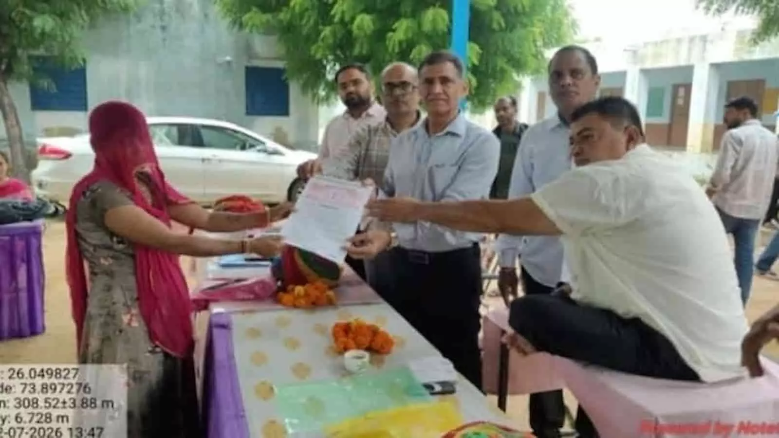 तस्वीर में दिख रही एक ग्रामीण महिला को सरकारी शिविर में अधिकारी दस्तावेज सौंपते हुए। तस्वीर में दिख रही एक ग्रामीण महिला को सरकारी शिविर में अधिकारी दस्तावेज सौंपते हुए।