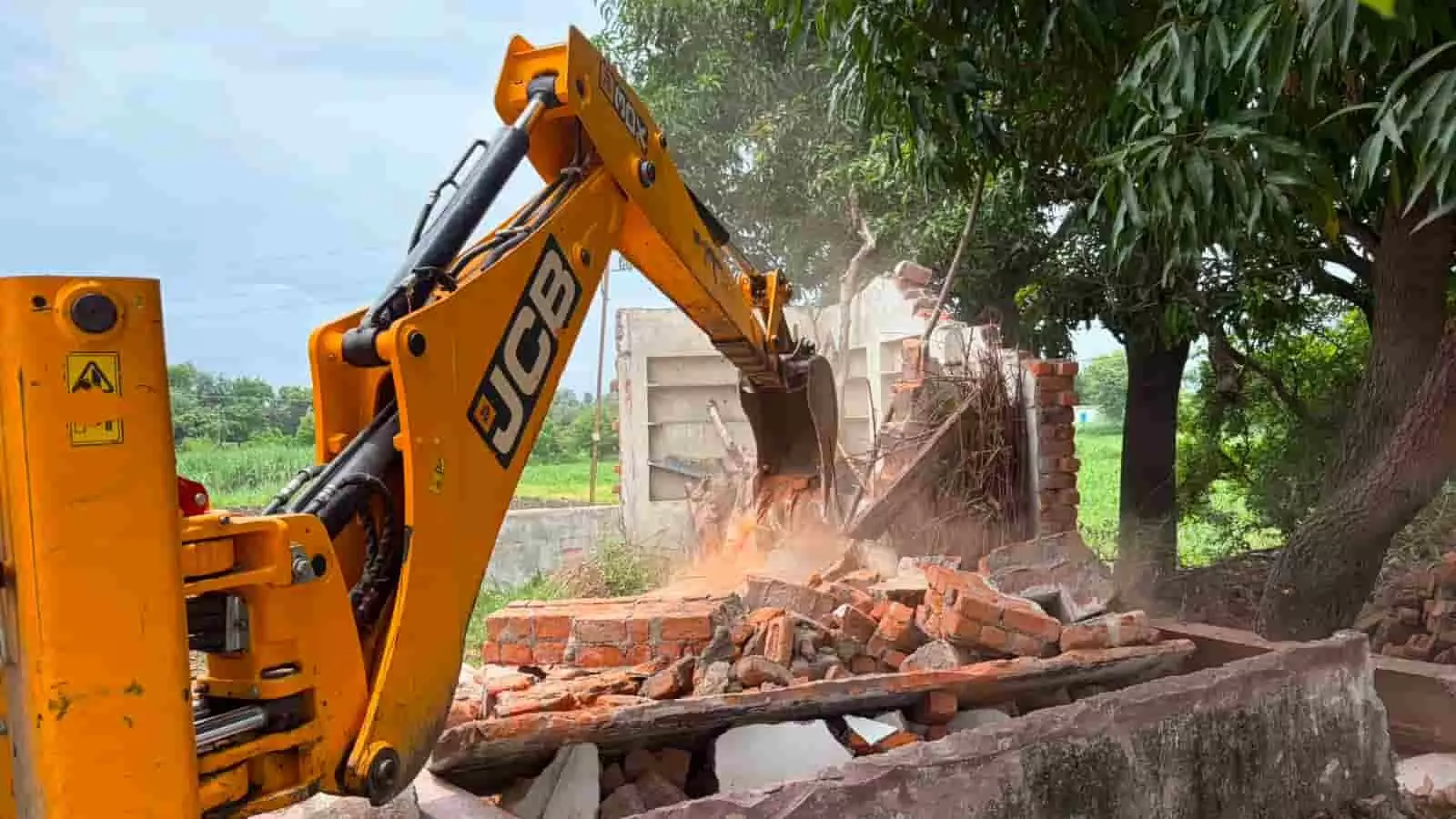 तस्वीर में एक जेसीबी मशीन सड़क किनारे बने अवैध पक्के निर्माण को तोड़ती हुई दिखाई दे रही है।