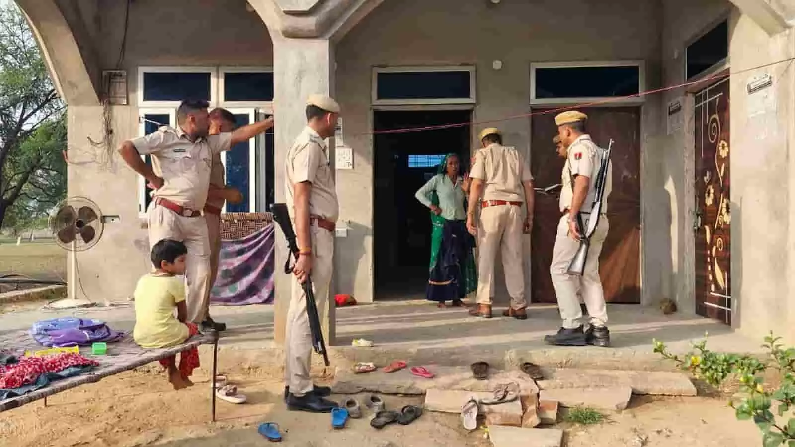 निर्माणाधीन घर के बाहर खड़े राजस्थान पुलिस के जवान महिला से पूछताछ करते हुए।