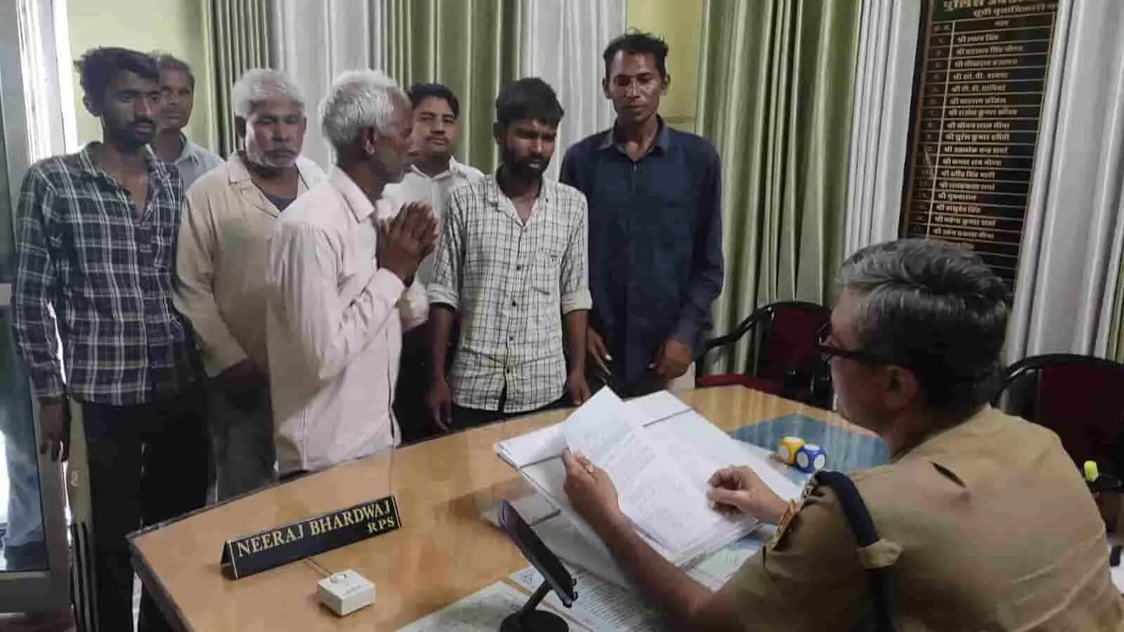 तस्वीर में पुलिस अधिकारी को टेबल पर दस्तावेज जांचते हुए कुछ लोग ज्ञापन सौंपते दिखे।