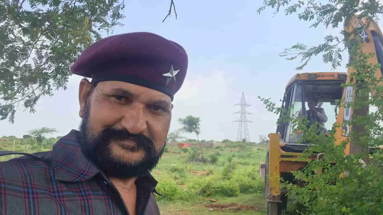 तस्वीर में एक व्यक्ति खुले मैदान में खुदाई मशीन के पास खड़ा दिखाई दे रहा है। तस्वीर में एक व्यक्ति खुले मैदान में खुदाई मशीन के पास खड़ा दिखाई दे रहा है।