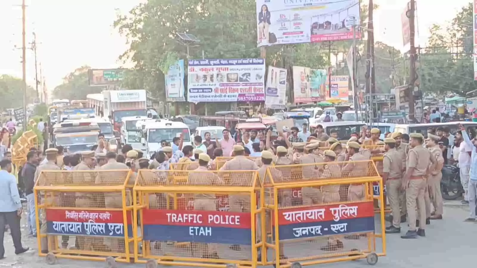एटा में सड़क पर बैरिकेडिंग के पीछे तैनात पुलिस बल और सामने खड़े प्रदर्शनकारी।