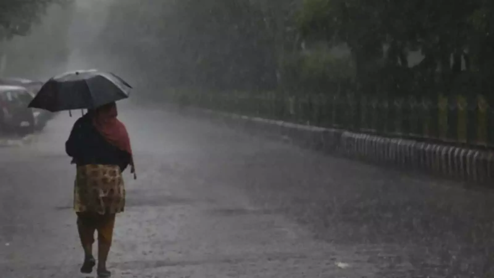 तस्वीर में एक व्यक्ति बारिश के दौरान सड़क पर छाता लेकर चलता हुआ दिख रहा है। तस्वीर में एक व्यक्ति बारिश के दौरान सड़क पर छाता लेकर चलता हुआ दिख रहा है।