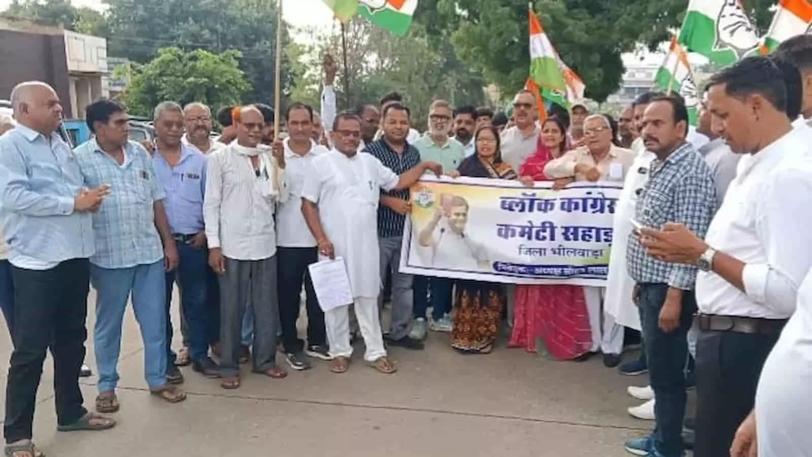 तस्वीर में सड़क पर कांग्रेस पार्टी के बैनर और झंडे के साथ खड़े कार्यकर्ता। तस्वीर में सड़क पर कांग्रेस पार्टी के बैनर और झंडे के साथ खड़े कार्यकर्ता।