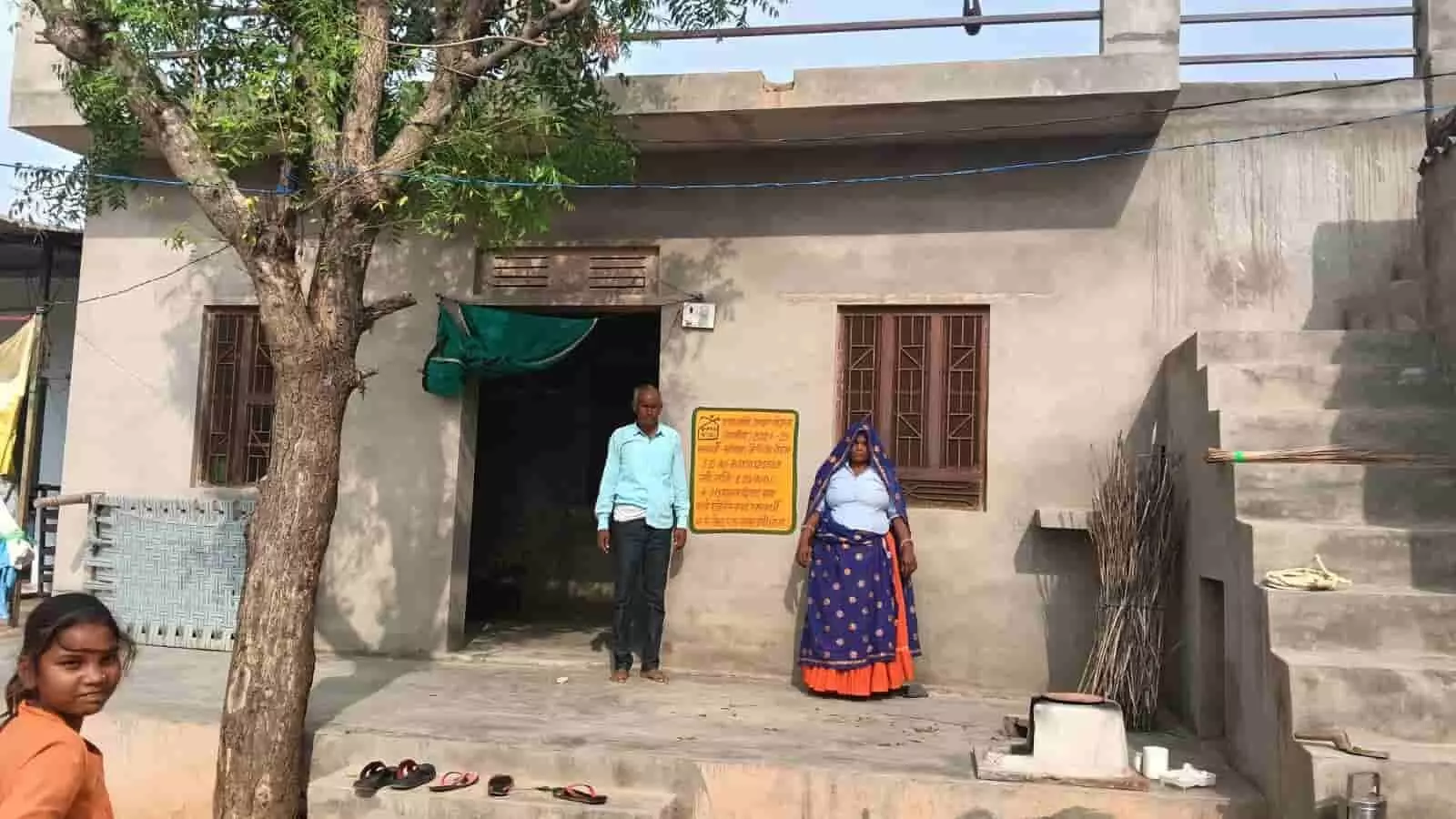 तस्वीर में नए पक्के मकान के सामने खड़े लाभार्थी और बच्ची ग्राम पंचायत में दिखाई दे रहे हैं।