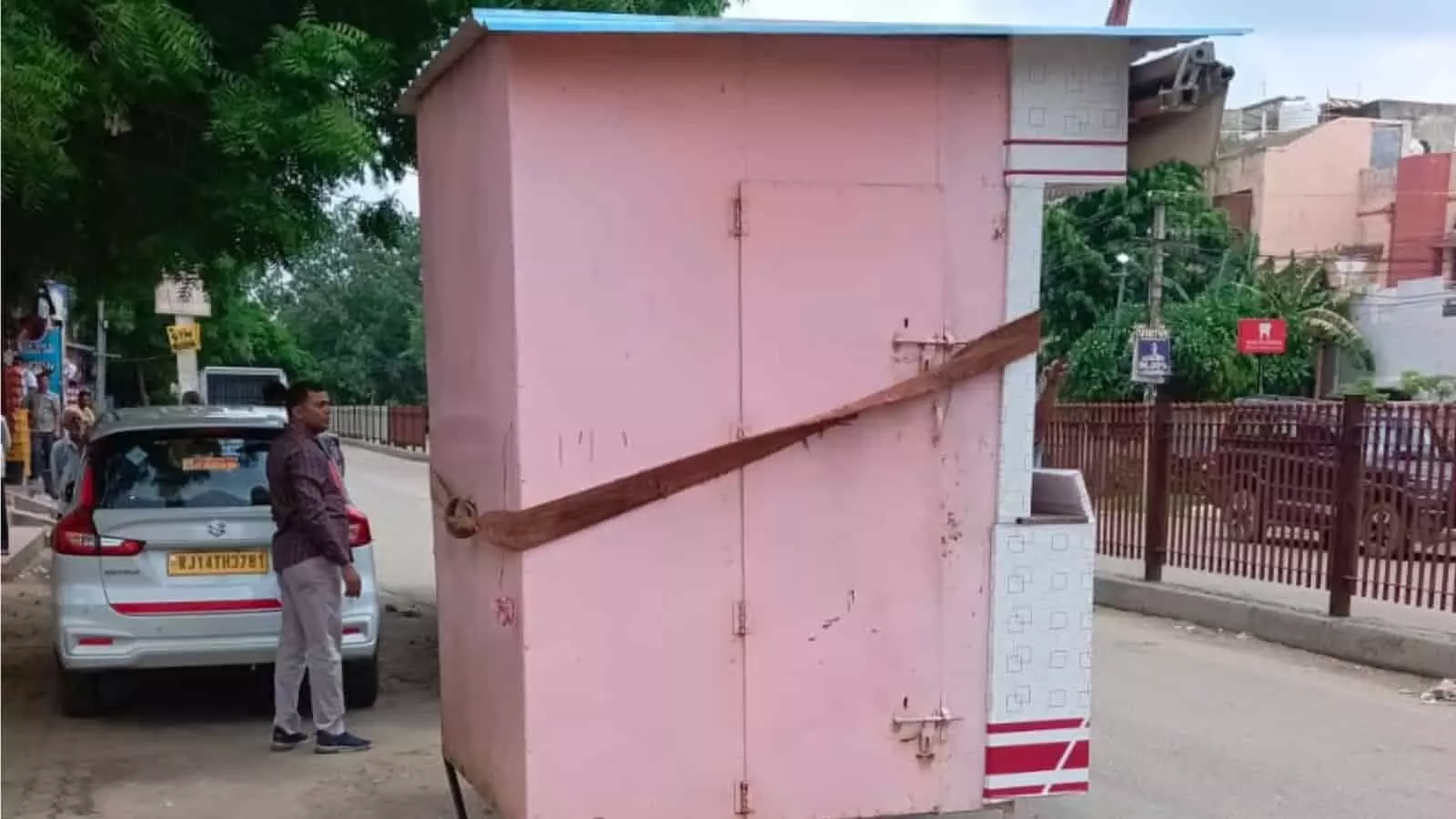 तस्वीर में सड़क किनारे रखा गुलाबी रंग का केबिन और पास खड़े निगम अधिकारी दिख रहे हैं। तस्वीर में सड़क किनारे रखा गुलाबी रंग का केबिन और पास खड़े निगम अधिकारी दिख रहे हैं।