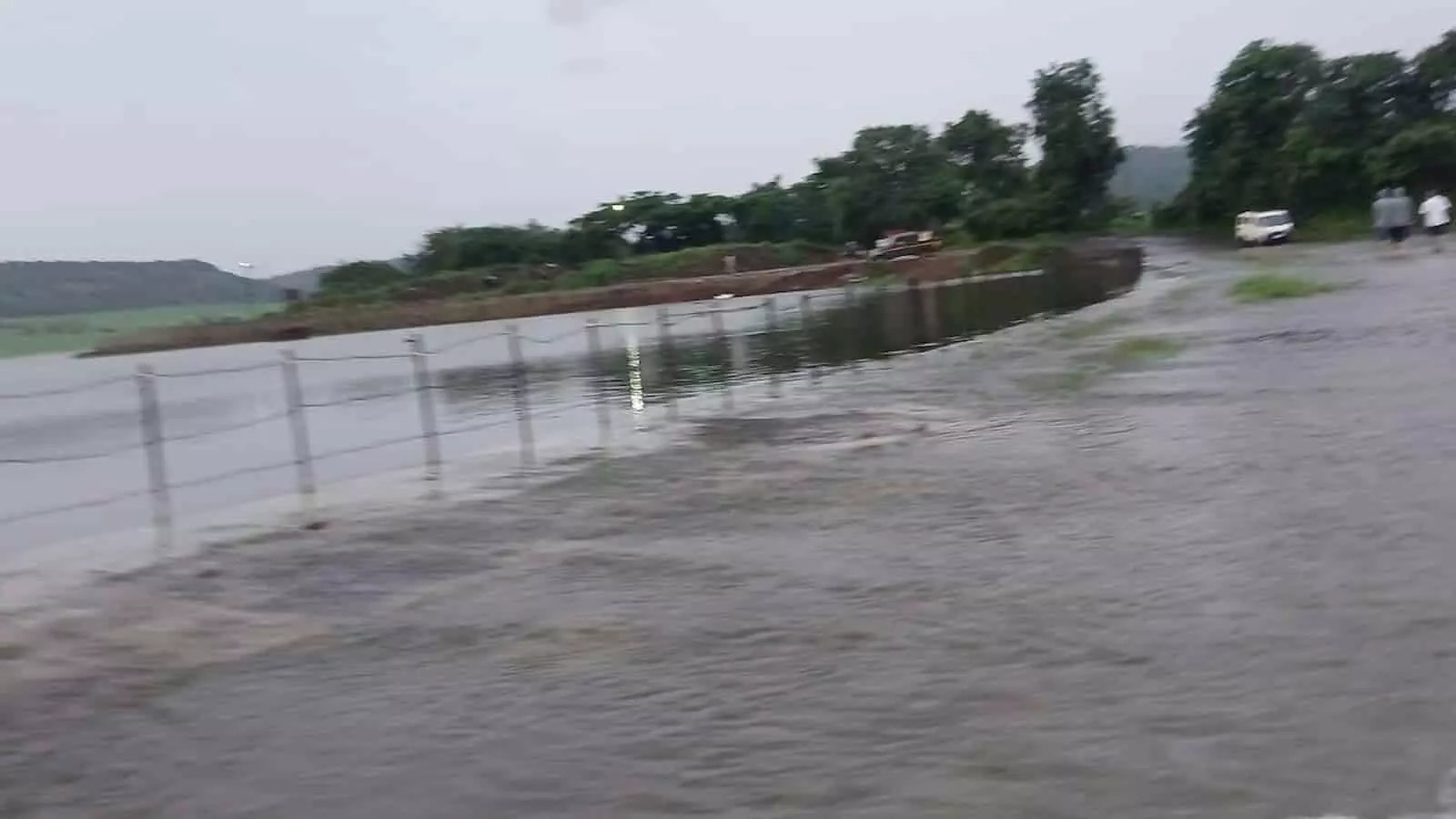तस्वीर में पानी से लबालब भरा तालाब और सड़क पर बहता पानी दिख रहा है। तस्वीर में पानी से लबालब भरा तालाब और सड़क पर बहता पानी दिख रहा है।