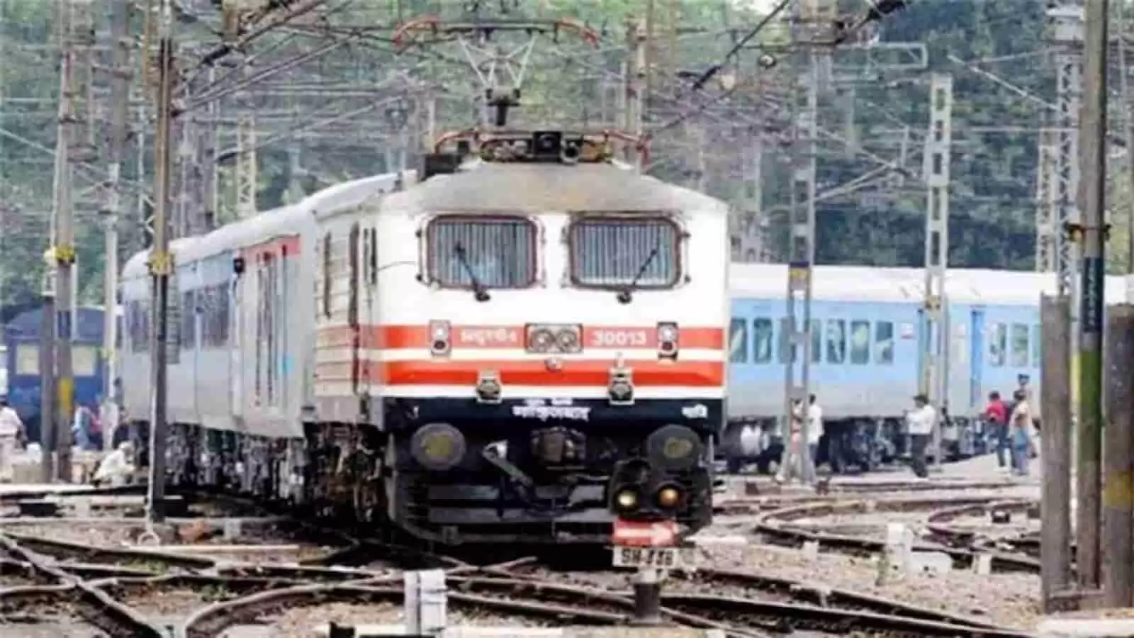 तस्वीर में रेलवे यार्ड में पटरियों पर खड़ी इलेक्ट्रिक यात्री ट्रेन और आसपास रेल डिब्बे दिखाई दे रहे हैं। तस्वीर में रेलवे यार्ड में पटरियों पर खड़ी इलेक्ट्रिक यात्री ट्रेन और आसपास रेल डिब्बे दिखाई दे रहे हैं।