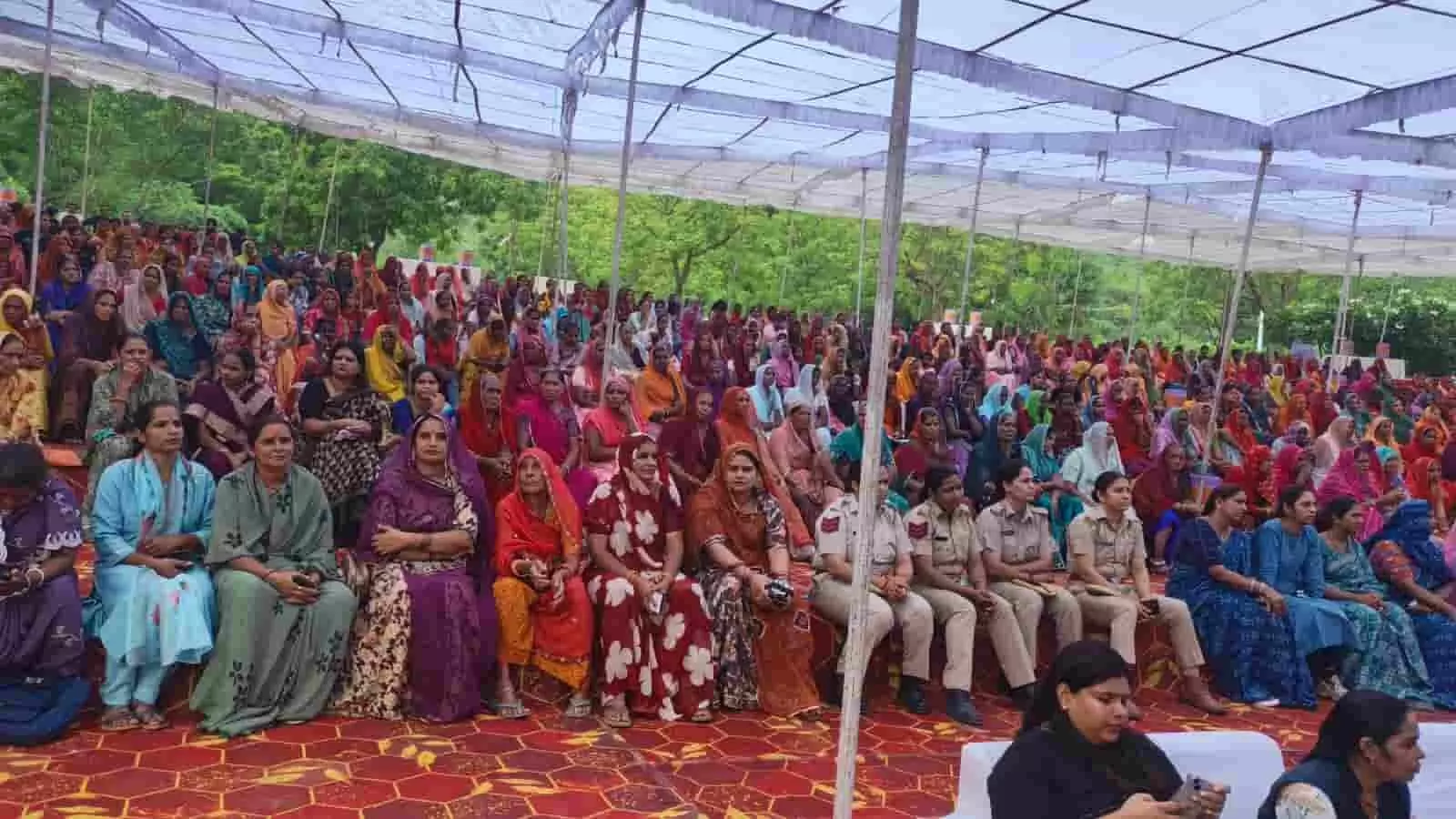 तस्वीर में पंडाल के नीचे बैठी महिलाएं और महिला पुलिसकर्मी संवाद कार्यक्रम में भाग लेती हुई।