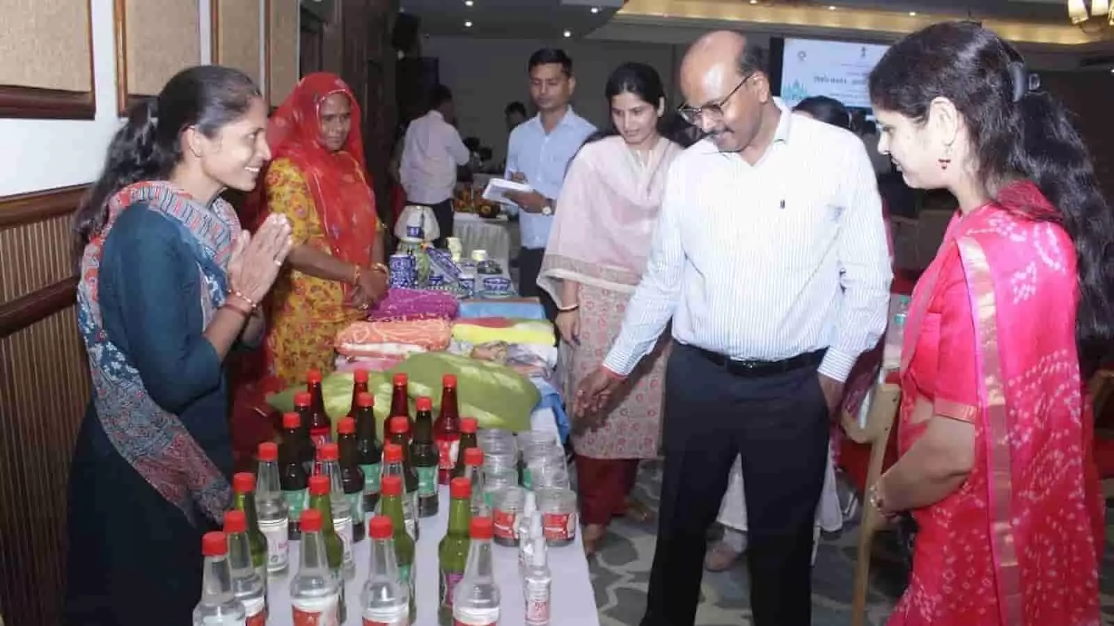 तस्वीर में दिख रही राजीविका प्रदर्शनी स्टॉल पर अधिकारी स्वयं सहायता समूह की महिलाओं से संवाद कर रहे हैं।