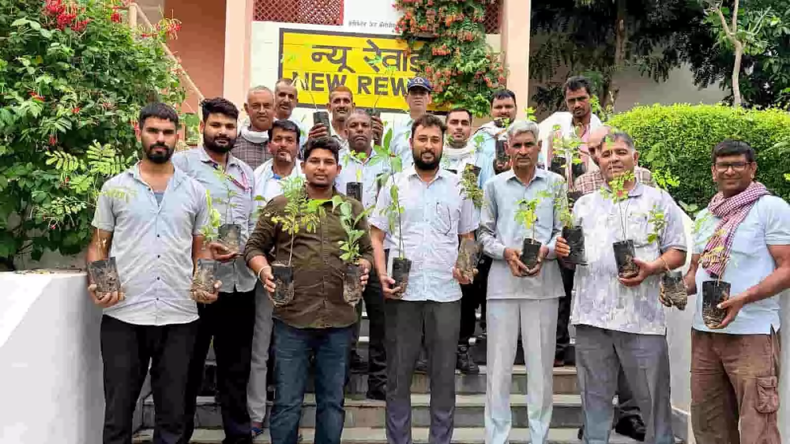 न्यू रेवाड़ी रेलवे स्टेशन परिसर में हाथों में छोटे पौधे थामे खड़े रेलवे कर्मचारी।