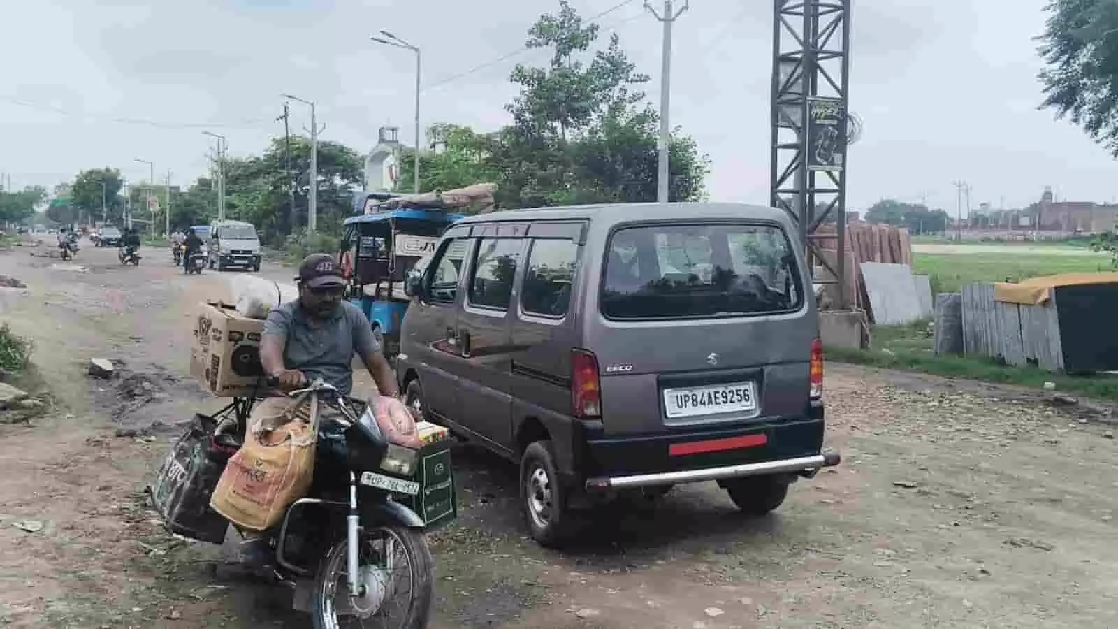 तस्वीर में अलीगंज के खराब रास्ते पर मोटरसाइकिल सवार व्यक्ति और कार दिखाई दे रहे हैं।