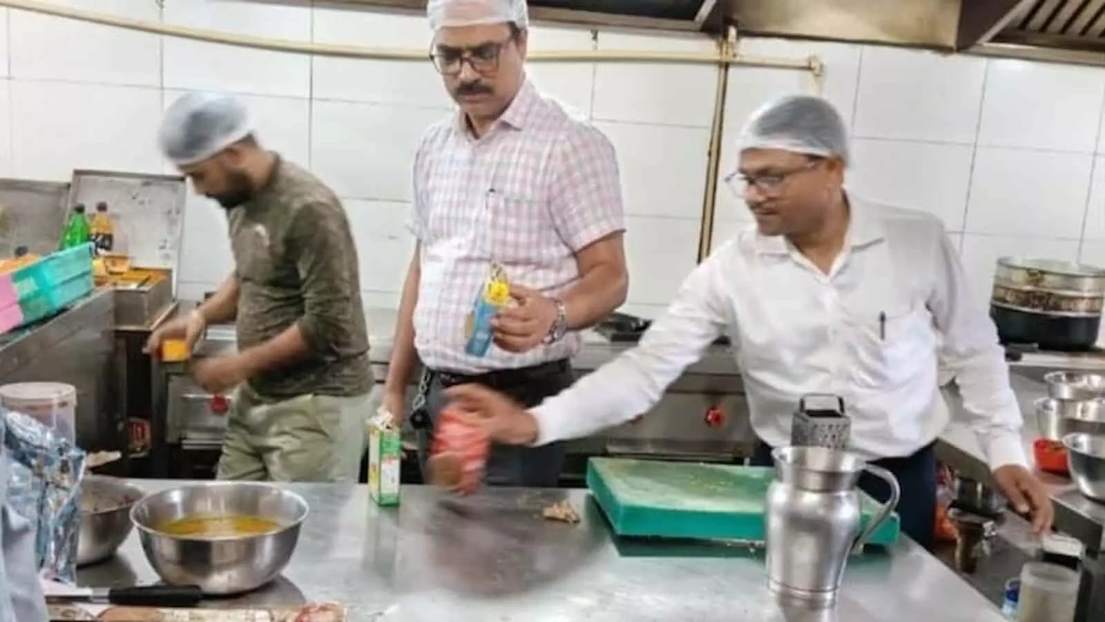 तस्वीर में रसोई के भीतर खाद्य सुरक्षा अधिकारी पैकेटबंद सामान की जांच करते दिख रहे हैं। तस्वीर में रसोई के भीतर खाद्य सुरक्षा अधिकारी पैकेटबंद सामान की जांच करते दिख रहे हैं।