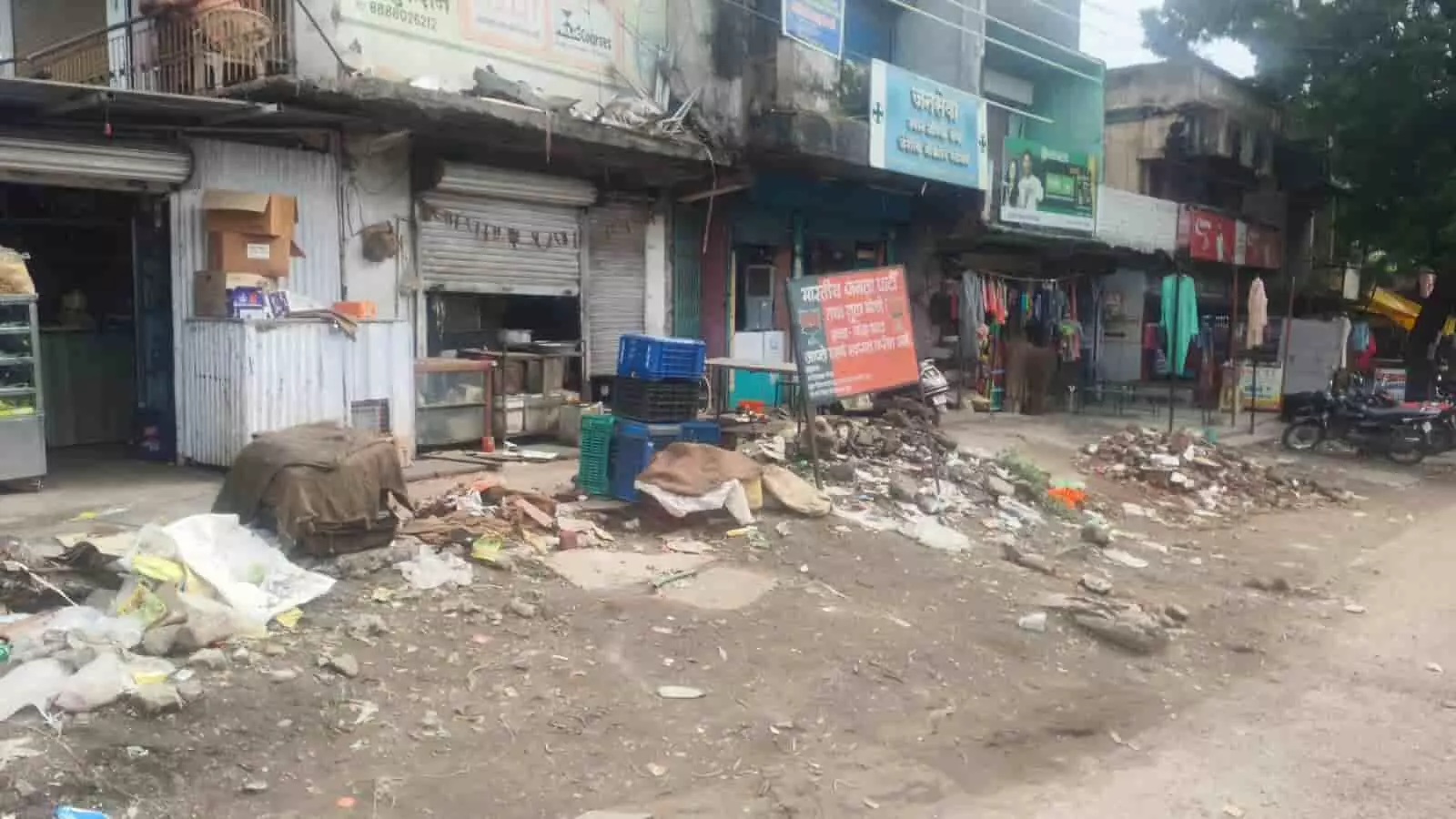 नांदा बाजार के मुख्य मार्ग पर दुकानों के सामने बिखरा मलबा और निर्माण कार्य स्थल दिख रहा है।