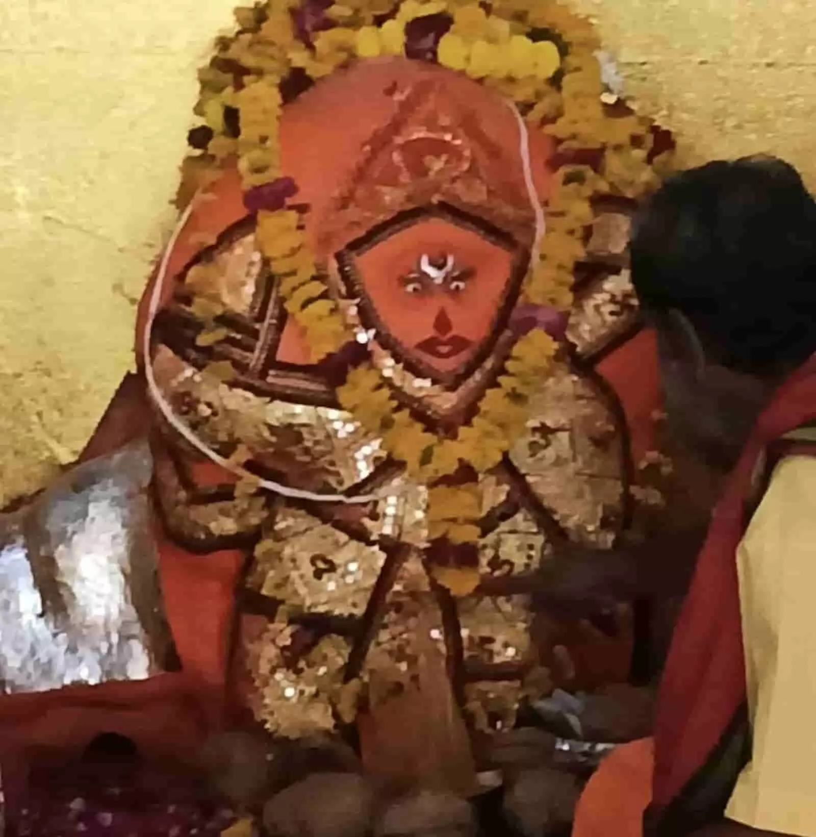 फूलों की माला से सजी हनुमान जी की मूर्ति के पास बैठा एक व्यक्ति पूजा कर रहा है। फूलों की माला से सजी हनुमान जी की मूर्ति के पास बैठा एक व्यक्ति पूजा कर रहा है।