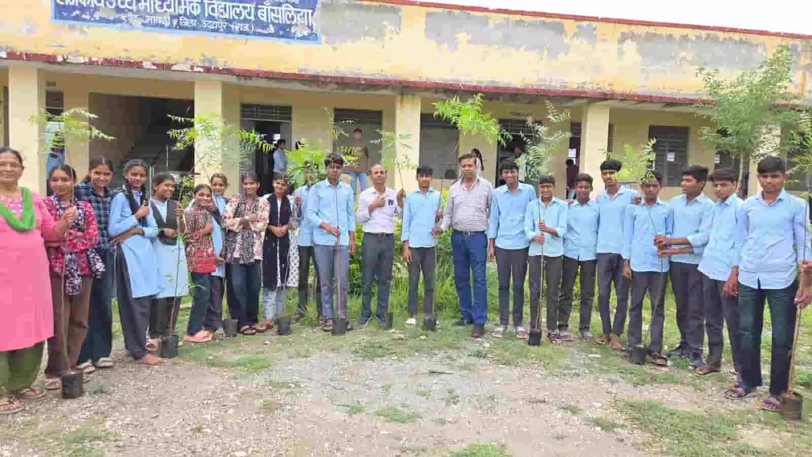 तस्वीर में राजकीय उच्च माध्यमिक विद्यालय बांसलिया के शिक्षक और छात्र हाथों में नीम के पौधे लेकर खड़े हैं।