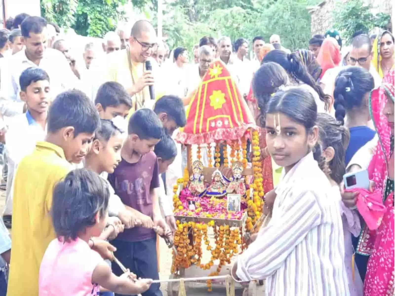 तस्वीर में बच्चे और ग्रामीण जलालपुर गांव में फूलों से सजे भगवान जगन्नाथ के रथ को खींच रहे हैं।