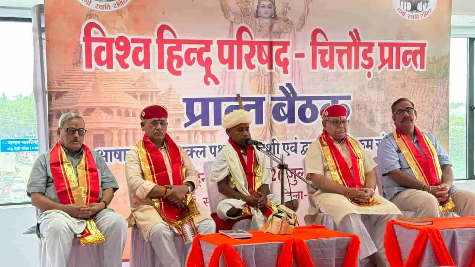 तस्वीर में मंच पर पांच लोग विहिप बैनर के सामने बैठे दिख रहे हैं। तस्वीर में मंच पर पांच लोग विहिप बैनर के सामने बैठे दिख रहे हैं।