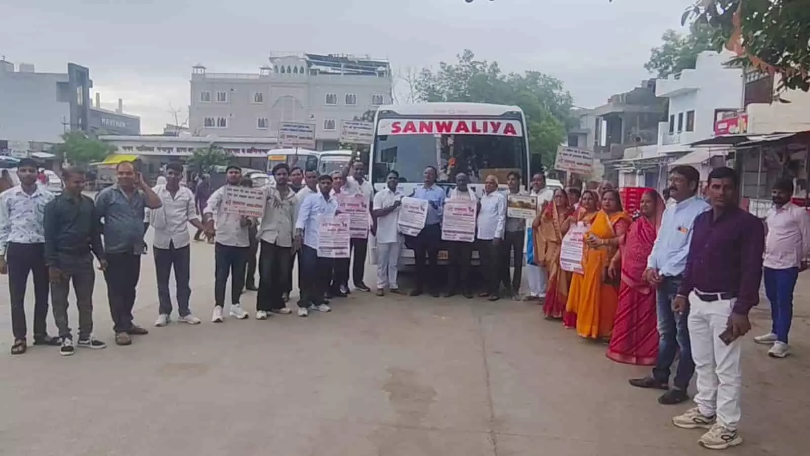 तस्वीर में बस के सामने पोस्टर हाथ में लिए खड़े लोग दिख रहे हैं। तस्वीर में बस के सामने पोस्टर हाथ में लिए खड़े लोग दिख रहे हैं।