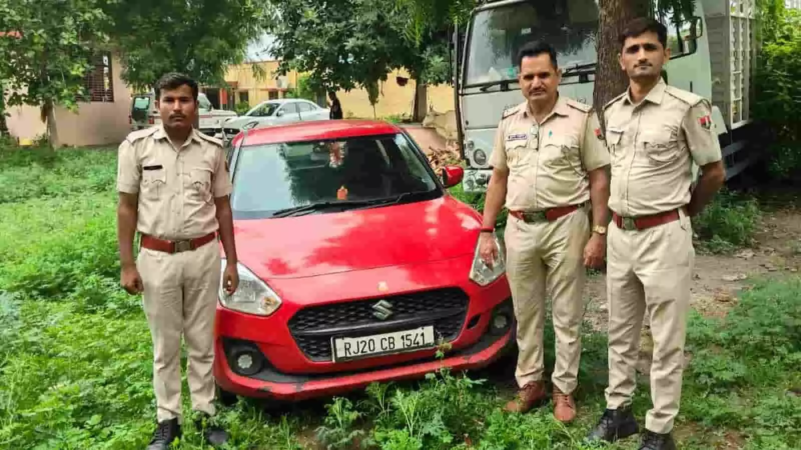 तस्वीर में पुलिसकर्मी झालावाड़ के बाड़े में जब्त लाल कार के पास खड़े हैं। तस्वीर में पुलिसकर्मी झालावाड़ के बाड़े में जब्त लाल कार के पास खड़े हैं।