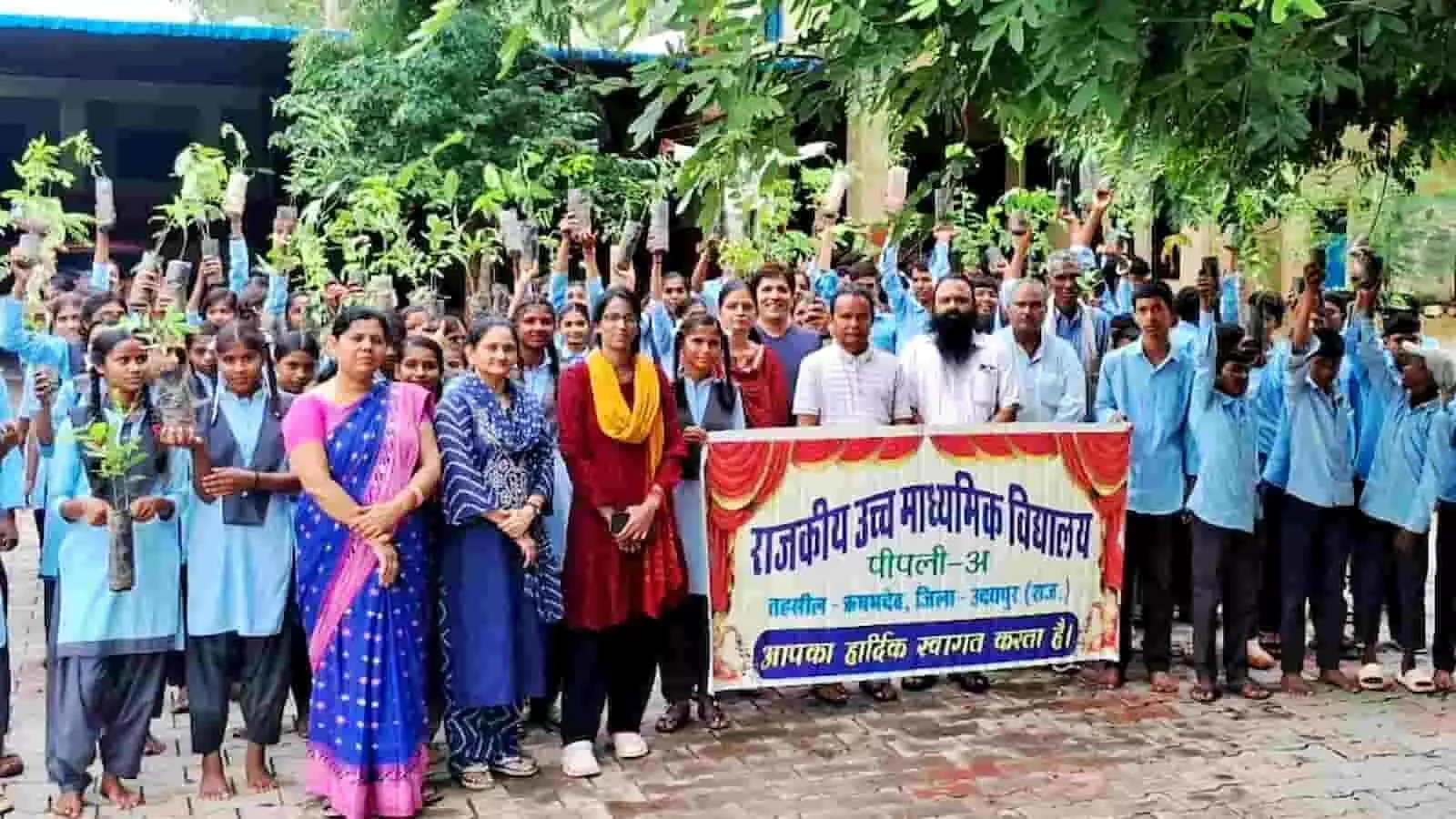 तस्वीर में विद्यालय परिसर में पौधे हाथ में लिए खड़े छात्र और शिक्षक दिखाई दे रहे हैं।
