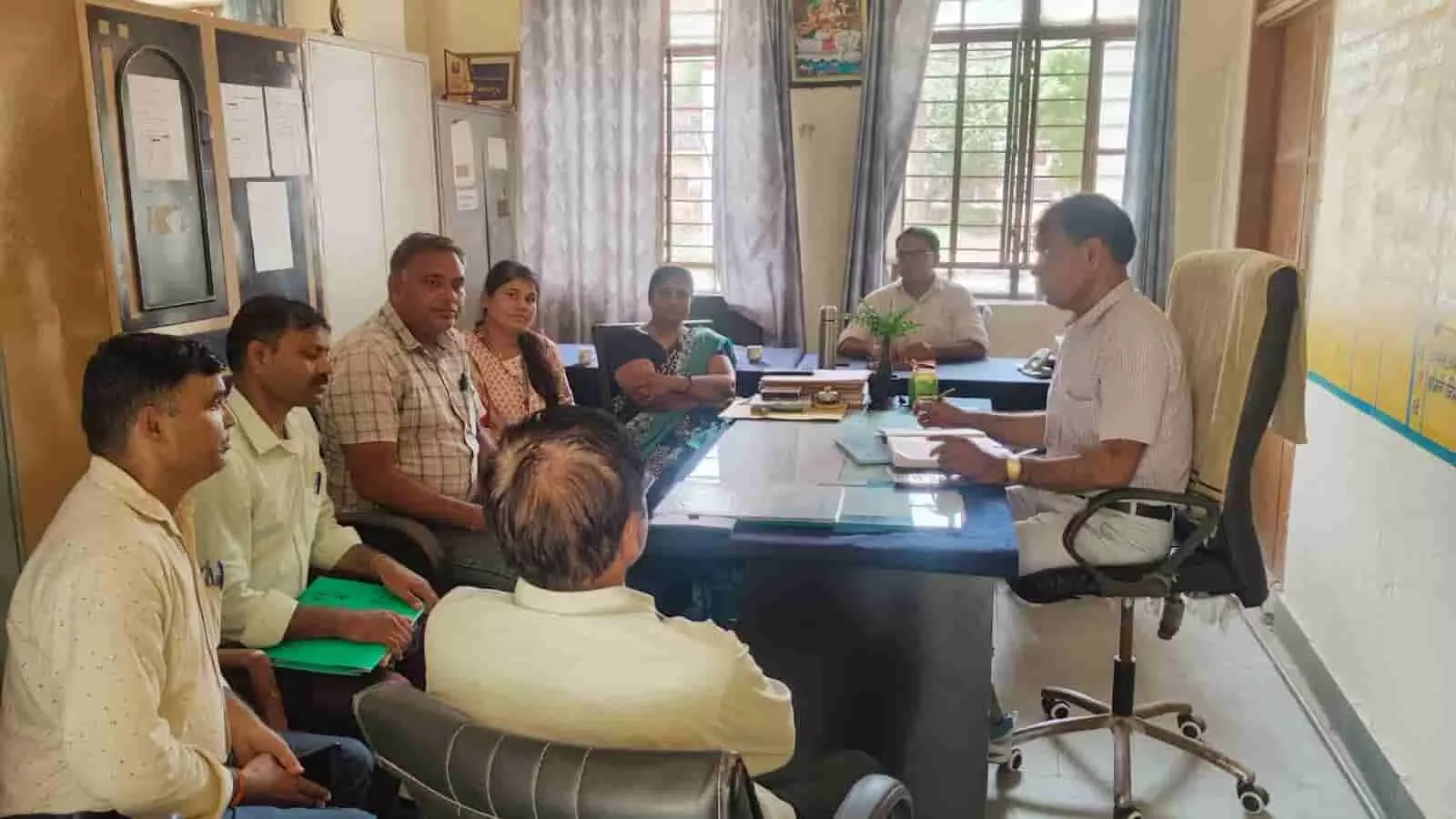 कार्यालय कक्ष में टेबल के पास बैठकर समीक्षा बैठक करते जिला शिक्षा अधिकारी और स्कूल स्टाफ। कार्यालय कक्ष में टेबल के पास बैठकर समीक्षा बैठक करते जिला शिक्षा अधिकारी और स्कूल स्टाफ।