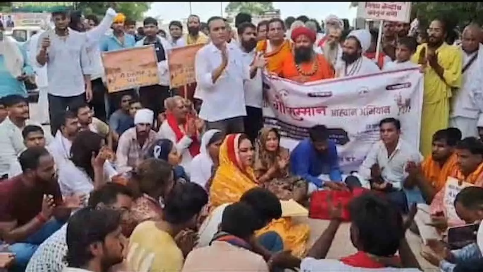 तस्वीर में डीग में बैनर थामकर प्रदर्शन करते गौ भक्त और साधु-संत दिख रहे हैं।