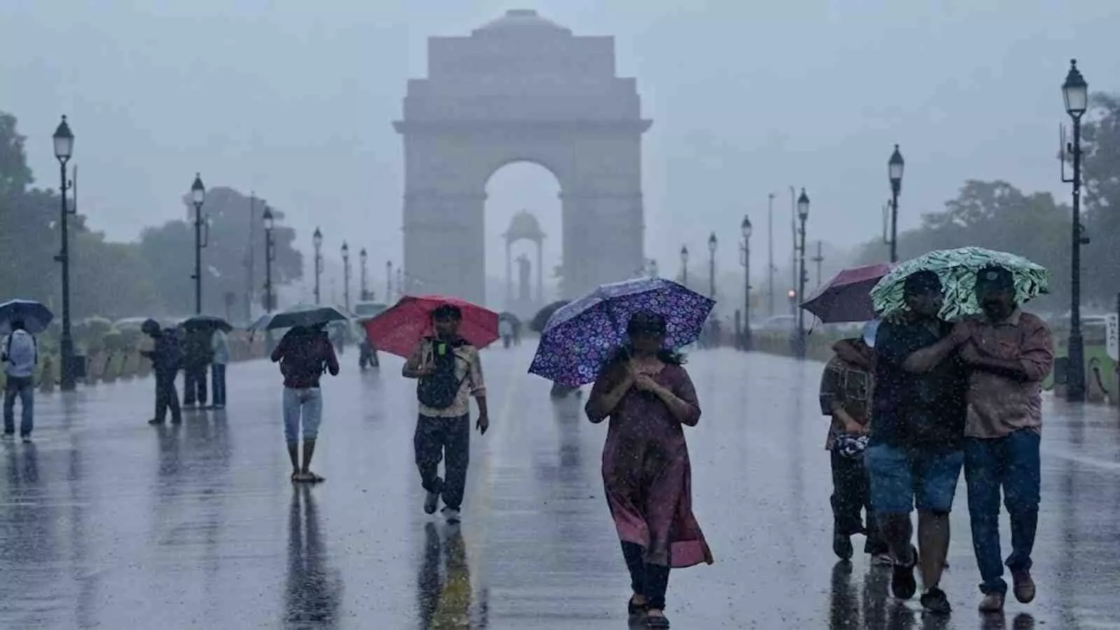 बारिश के बीच छाते लेकर चलते लोग इंडिया गेट नई दिल्ली में मॉनसून सक्रिय रहने के दौरान।