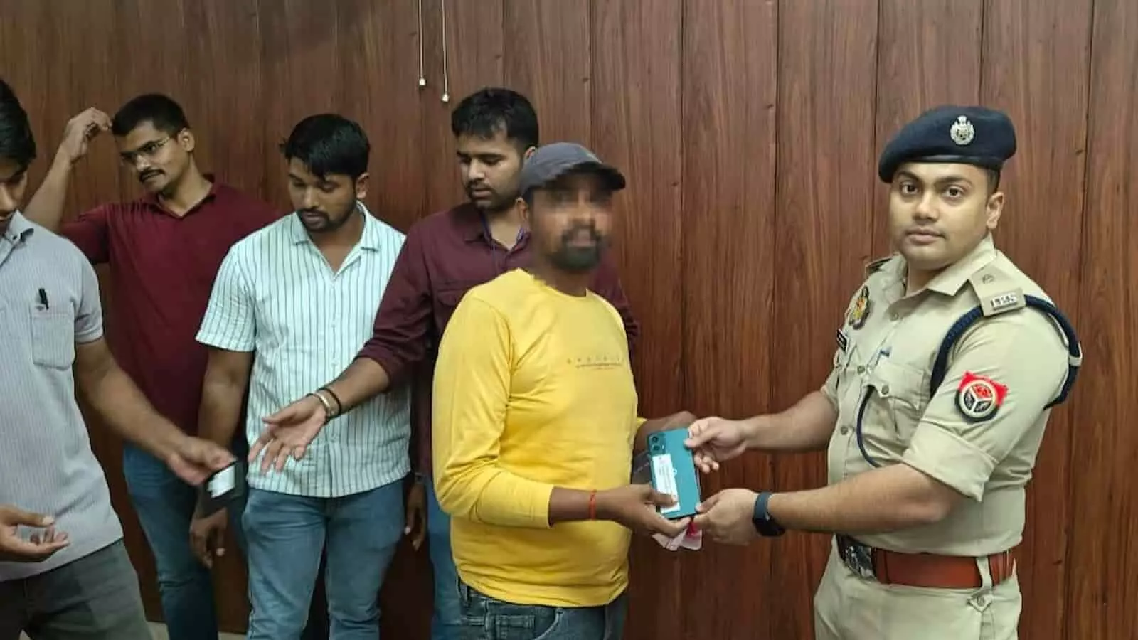 तस्वीर में पुलिस अधिकारी चंदौली में एक नागरिक को उसका खोया हुआ मोबाइल फोन सौंप रहा है।
