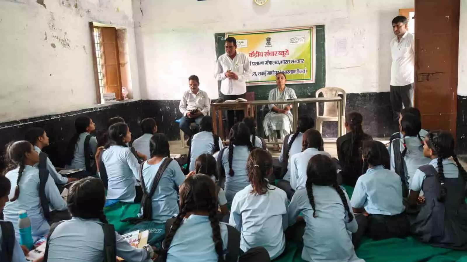 तस्वीर में केंद्रीय संचार ब्यूरो के प्रभारी छात्राओं को विश्व प्रकृति संरक्षण दिवस के बारे में समझाते दिख रहे हैं।