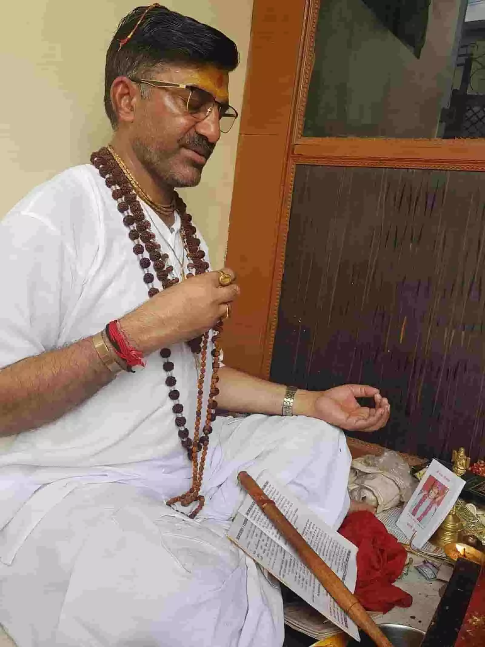 तस्वीर में ज्योतिषाचार्य डॉ. पंडित पुरुषोत्तम गौड़ पूजा स्थल पर रुद्राक्ष की माला से जप करते हुए दिख रहे हैं।
