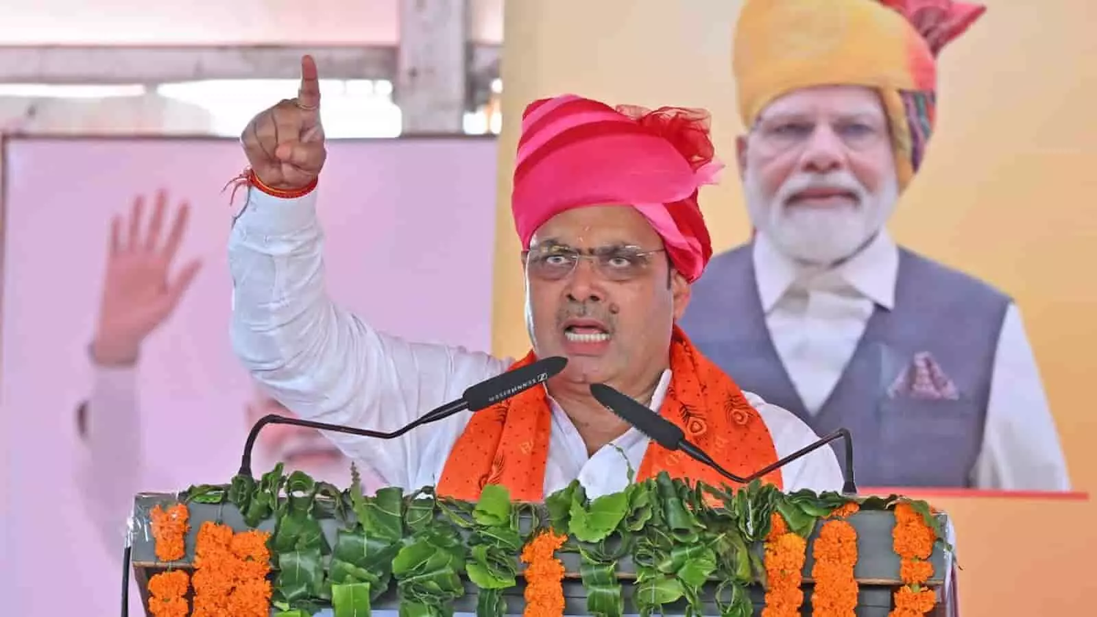तस्वीर में गुलाबी साफा पहने राजस्थान के मुख्यमंत्री भजनलाल शर्मा मंच पर भाषण देते हुए। तस्वीर में गुलाबी साफा पहने राजस्थान के मुख्यमंत्री भजनलाल शर्मा मंच पर भाषण देते हुए।
