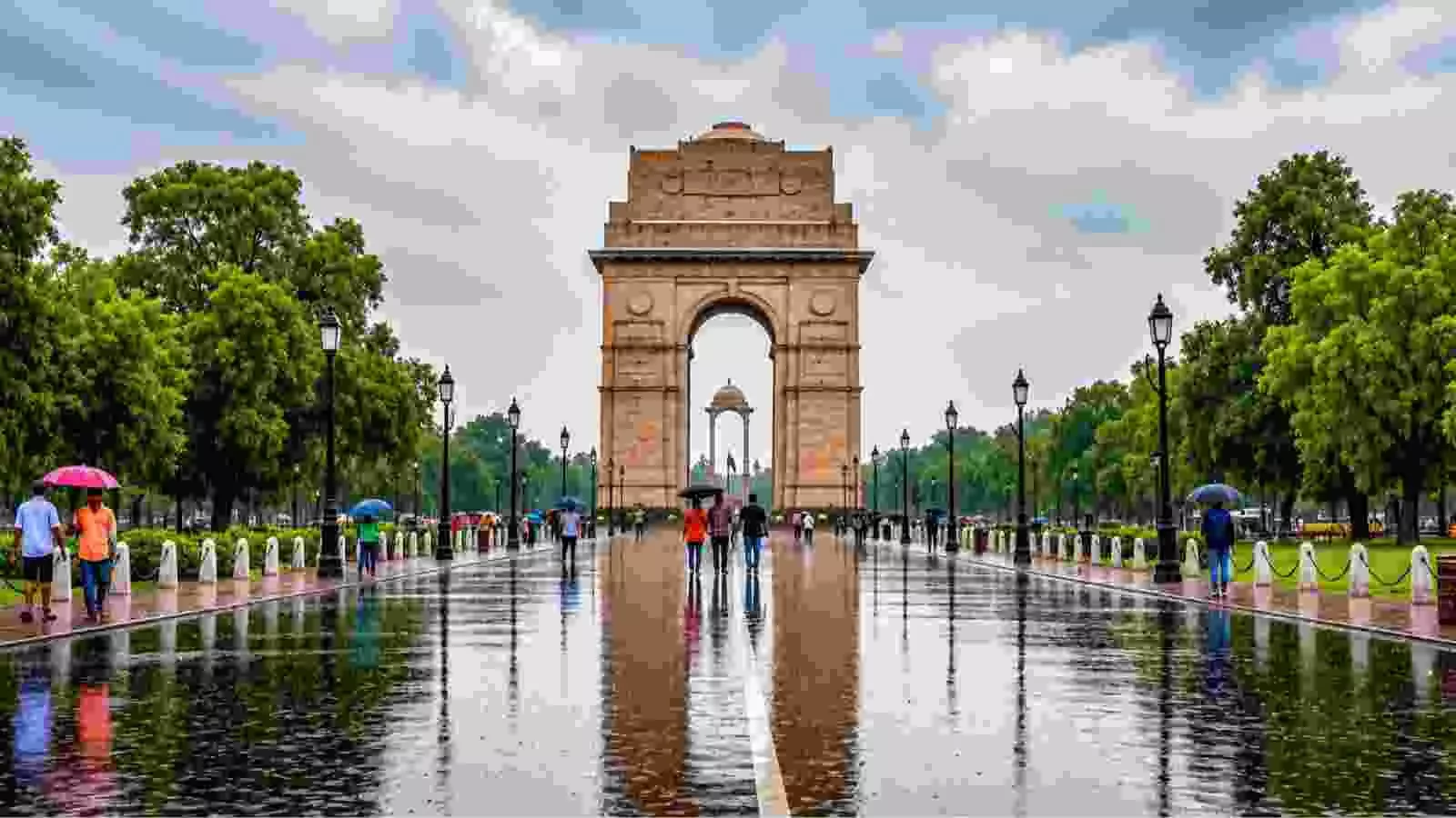बारिश के दौरान इंडिया गेट के पास छाता लेकर चलते लोग और भीगती सड़कें। बारिश के दौरान इंडिया गेट के पास छाता लेकर चलते लोग और भीगती सड़कें।
