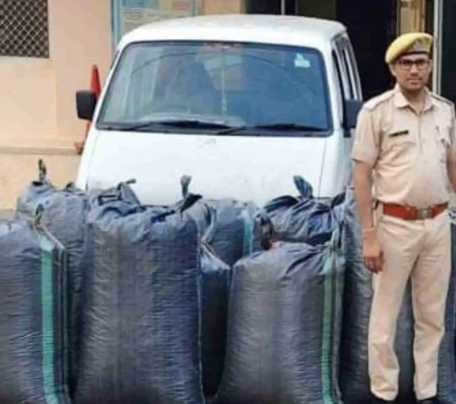 तस्वीर में सफेद कार के आगे रखे काले कट्टों के पास एक पुलिसकर्मी खड़ा दिख रहा है। तस्वीर में सफेद कार के आगे रखे काले कट्टों के पास एक पुलिसकर्मी खड़ा दिख रहा है।