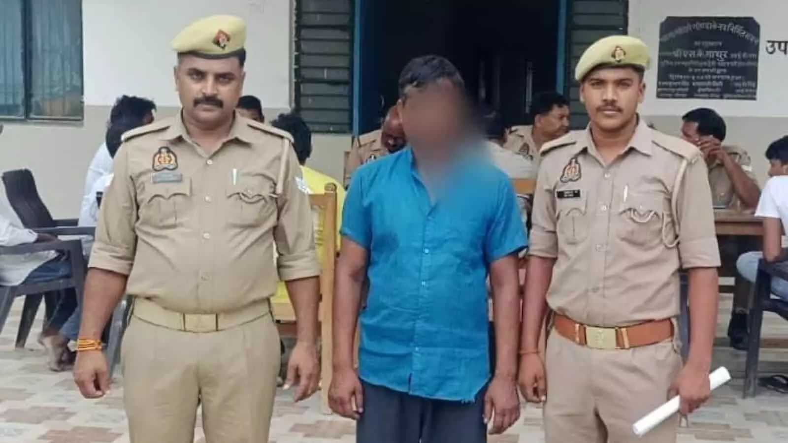 तस्वीर में दो पुलिसकर्मियों के बीच खड़ा आरोपी पुलिस स्टेशन परिसर में दिख रहा है। तस्वीर में दो पुलिसकर्मियों के बीच खड़ा आरोपी पुलिस स्टेशन परिसर में दिख रहा है।