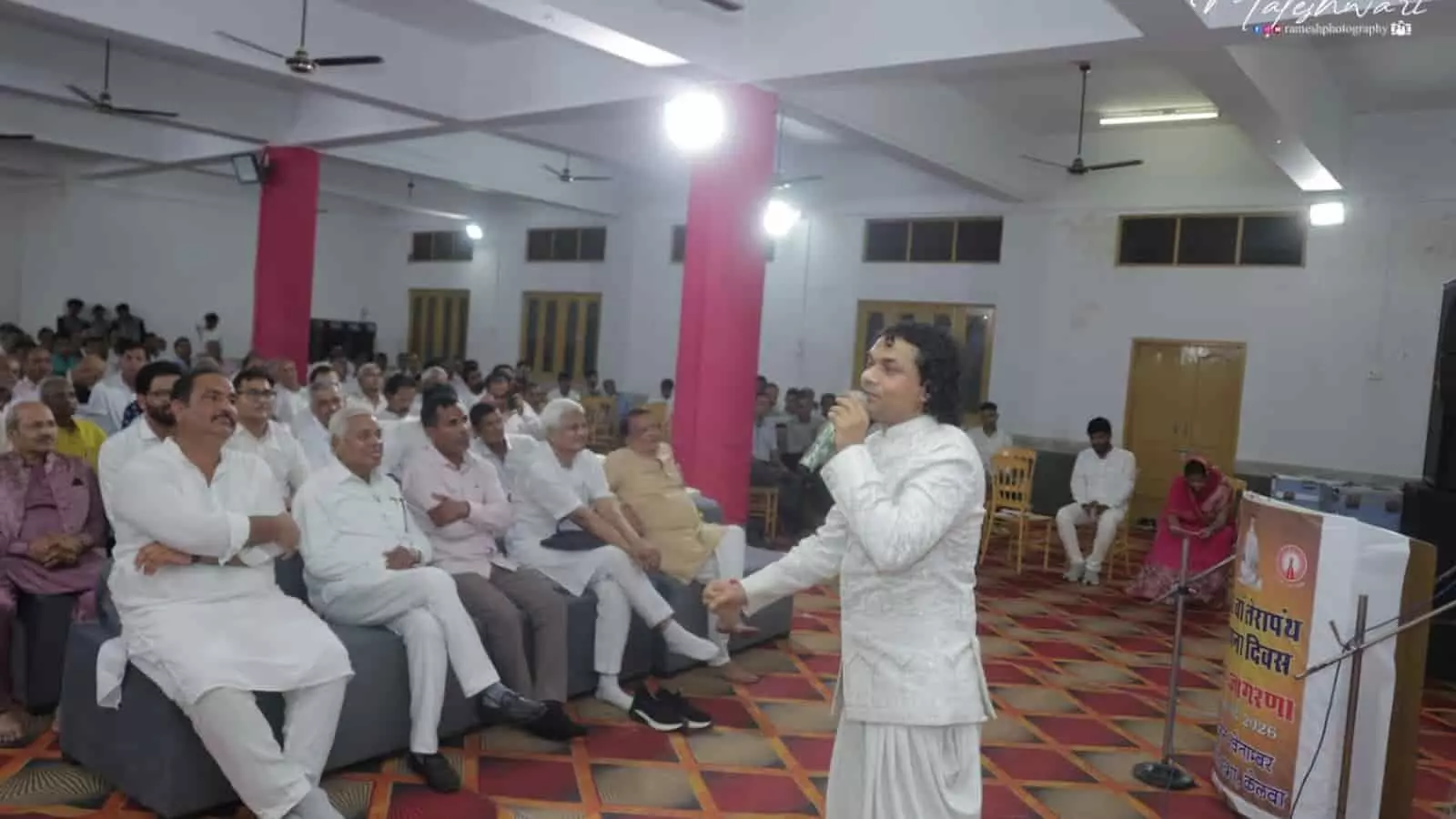 हॉल में माइक लेकर प्रस्तुतियां देते भजन गायक और सामने बैठे श्रद्धालु दिख रहे हैं। हॉल में माइक लेकर प्रस्तुतियां देते भजन गायक और सामने बैठे श्रद्धालु दिख रहे हैं।