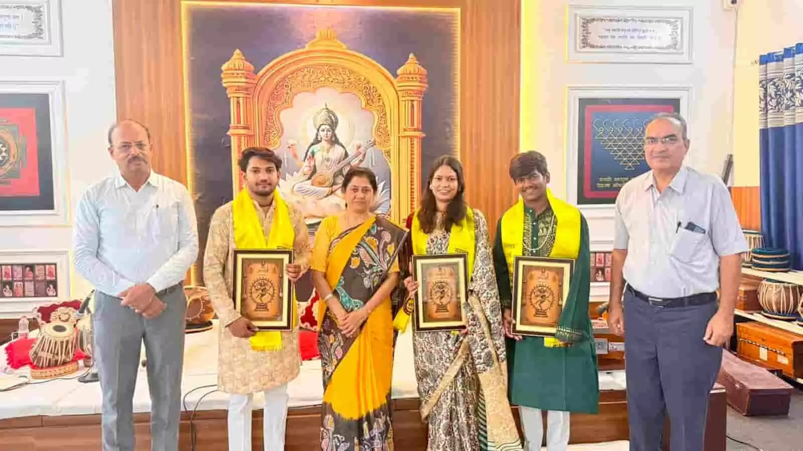 तस्वीर में संगीत सभा कार्यक्रम के दौरान सम्मानित कलाकारों और अतिथियों को स्मृति-चिह्न के साथ खड़े दिखाया गया है। तस्वीर में संगीत सभा कार्यक्रम के दौरान सम्मानित कलाकारों और अतिथियों को स्मृति-चिह्न के साथ खड़े दिखाया गया है।