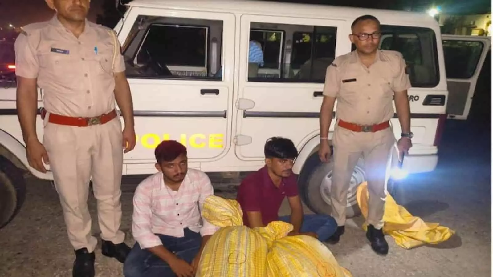 तस्वीर में पुलिस वाहन के पास खड़े पुलिसकर्मी और जमीन पर बैठे संदिग्ध आरोपी नजर आ रहे हैं। तस्वीर में पुलिस वाहन के पास खड़े पुलिसकर्मी और जमीन पर बैठे संदिग्ध आरोपी नजर आ रहे हैं।
