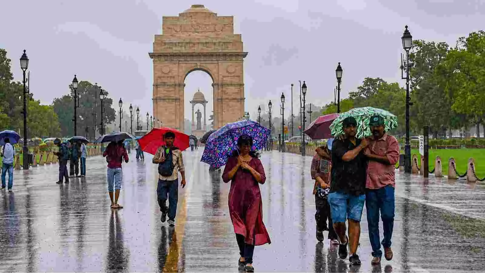 छतरियों के साथ लोग दिल्ली में इंडिया गेट के पास बारिश के बीच चल रहे हैं। छतरियों के साथ लोग दिल्ली में इंडिया गेट के पास बारिश के बीच चल रहे हैं।