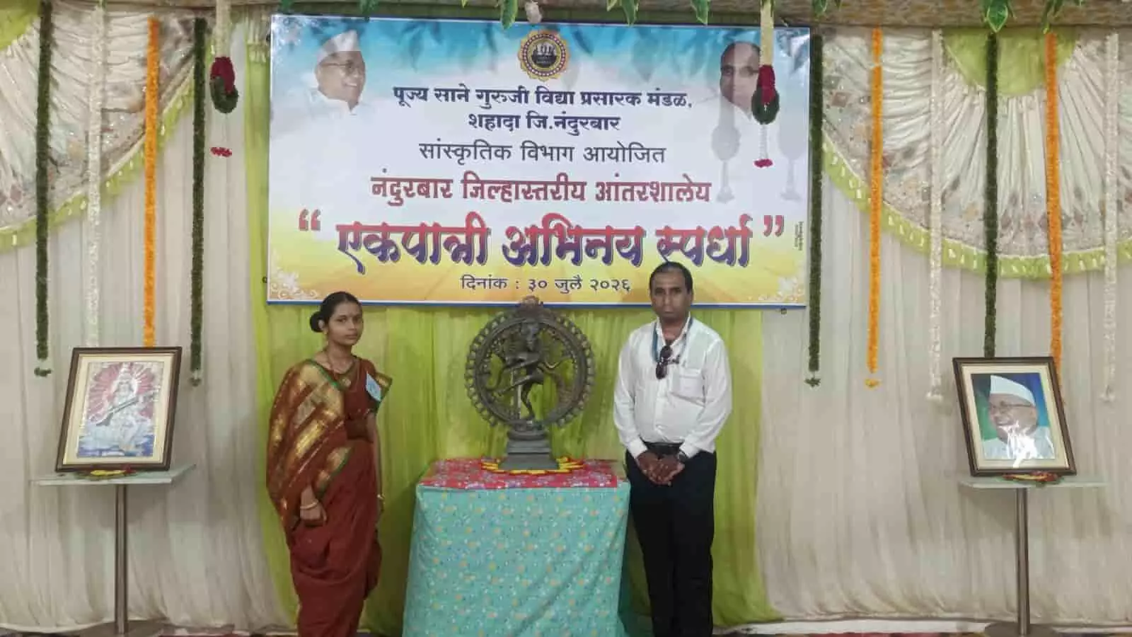 तस्वीर में छात्रा और शिक्षक नंदुरबार जिलास्तरीय अभिनय प्रतियोगिता के बैनर के सामने खड़े हैं। तस्वीर में छात्रा और शिक्षक नंदुरबार जिलास्तरीय अभिनय प्रतियोगिता के बैनर के सामने खड़े हैं।